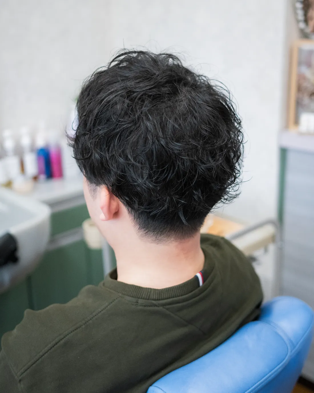ナチュラルパーマをかけたメンズショートヘアを左斜め後ろから撮影した後ろ姿